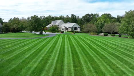 Striped-lawn-leading-to-a-large-suburban-home-with-trees