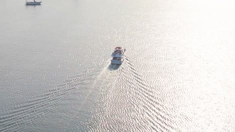 Blick-Aus-Der-Vogelperspektive-Auf-Ein-Großes-Boot-Bei-Sonnenaufgang-In-Ruhigem-Wasser,-Das-Licht-Reflektiert