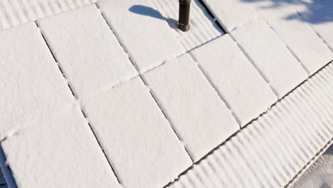 Aerial-close-up-around-snow-covered-solar-panels-on-a-house-roof,-winter-day