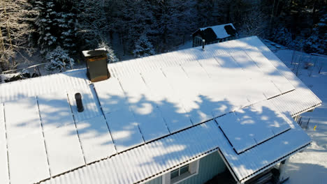 Aerial-view-rising-around-snowy-sunlight-collectors,-on-a-house-roof,-winter-day