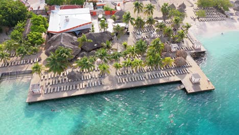 Sunrise-light-glistens-on-water-and-tropical-resort-at-Zanzibar-beach-Jan-Thiel-Curacao,-aerial