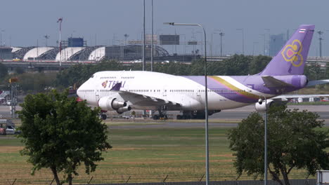 Thai-Airways,-the-flag-carrier-of-Thailand-stands-at-its-designated-space-in-Suvarnabhumi-Airport-in-Lat-Krabang-district-in-Bangkok,-Thailand