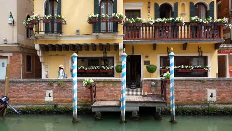 Woman-walking-past-private-dock-and-apartment-next-to-Venetian-canal