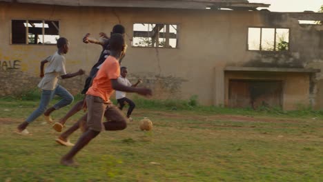 Boy-in-orange-shirt-plays-football-passing-through-several-defenders-as-it-moves-forward,-soccer-field,-Kumasi,-Ghana