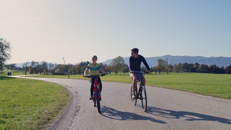 Young-smiling-couple-enjoying-a-bike-ride-in-the-autumn-countryside,-front-view
