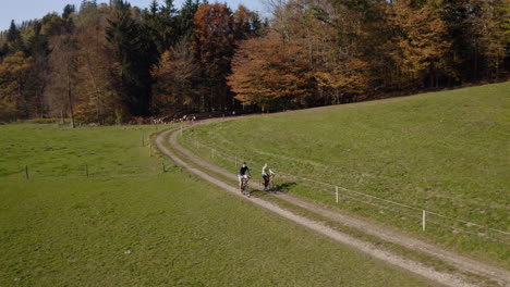Two-cyclists-enjoying-a-cycling-holiday-in-the-countryside-in-autumn,-aerial