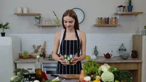 Smiling-young-girl-eating-fresh-raw-vegetable-salad-posing-at-kitchen-having-positive-emotion