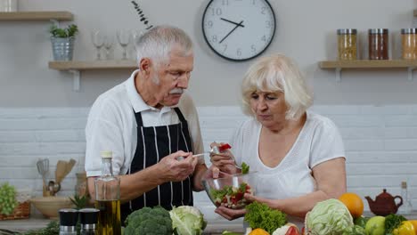 Senior-woman-and-man-feeding-each-other-with-fresh-raw-vegetable-salad.-Eco-food-eating-diet