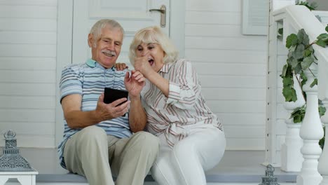 Älteres-Kaukasisches-Paar-Nutzt-Digitales-Tablet-Auf-Der-Veranda-Zu-Hause.-Viel-Spaß-Beim-Online-Shopping,-Neuigkeiten