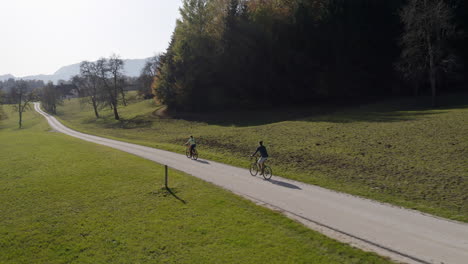 Couple-of-cyclists-touring-and-exploring-a-landscape-by-bicycle,-aerial-shot