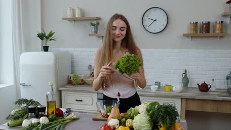Happy-girl-dancing,-having-fun-and-cooking-salad-with-raw-vegetables.-Throwing-pieces-of-lettuce