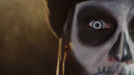Close-up-shot-of-face-in-skeleton-Halloween-makeup-opening-eyes-with-white-pupil,-trying-to-scare