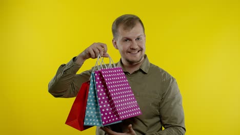 Man-raising-shopping-bags,-looking-satisfied-with-purchase,-enjoying-discounts-on-Black-Friday