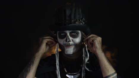 Sinister-man-with-horrible-Halloween-skeleton-makeup-puts-on-headphones,-starts-dancing,-celebrating