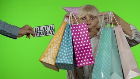 Advertisement-inscription-Black-Friday-appears-next-to-joyful-grandmother-with-shopping-bags