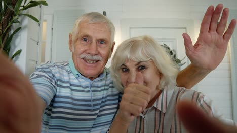 Senior-man,-woman-making-selfie-video-call,-embracing,-laughing,-waving-hands,-in-porch-at-home
