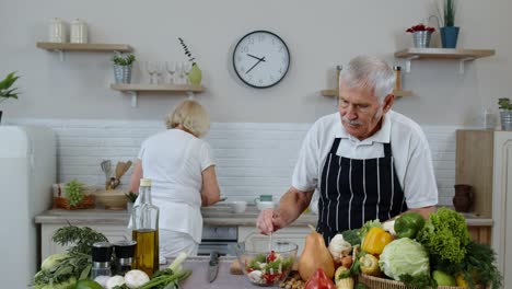 Elderly-grandparents-in-kitchen-interior.-Senior-woman-and-man-cooking-salad-with-fresh-vegetables