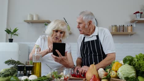 Vegane-ältere-Großeltern-Suchen-Online-Auf-Einem-Digitalen-Tablet-Nach-Einem-Kulinarischen-Rezept-Und-Kochen-Salat
