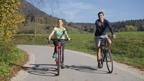 Couple-enjoying-cycling-in-the-countryside-during-fall-weekend-trip,-front-view