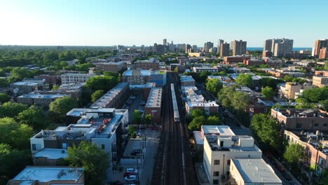 Elevated-train-passing-through-a-Chicago-suburb-with-a-backdrop-of-greenery-and-cityscape