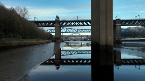 Wunderschöne-Spiegelung-Der-Brücken-Am-Fluss-Tyne,-Newcastle,-Während-Wir-Hinter-Dem-Pfosten-Der-Redheugh-Bridge-Hinüberschwenken