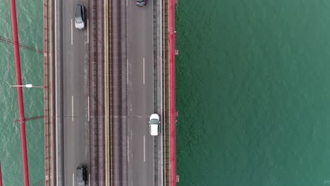 Aerial-close-up-view-o-cars-driving-on-Lisbon-Ponte-25-de-Abril-suspension-bridge-at-sunset,-Portugal