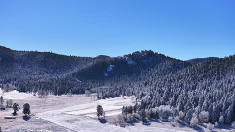 Cold-iced-melting-field-open-space-white-sunny-December-winter-Christmas-Xmas-frosted-Aspen-trees-forest-first-snow-aerial-cinematic-drone-bluebird-Evergreen-Colorado-Rocky-Mountain-scene-slow-upward