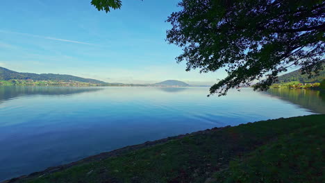 Ein-Ruhiger-Blauer-See,-Weithin-Umgeben-Von-Bergen-Und-Grünen-Bäumen-Bei-Sonnigem-Wetter
