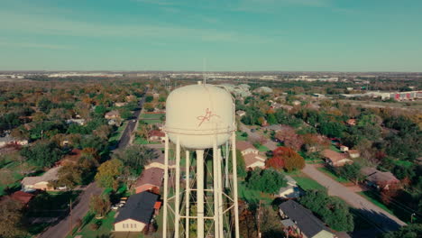 Georgetown,-Texas-water-tower-and-neighborhood-on-blue-sky-sunny-fall-day,-aerial-drone-tilt-down-in-Austin,-Texas-suburb