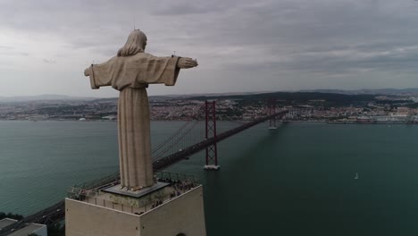 Aerial-view-of-Lisbon-cityscape-showing-Christ-the-King-statue-and-25-de-Abril-bridge-over-the-Tejo-river-by-day-in-Lisbon,-Portugal