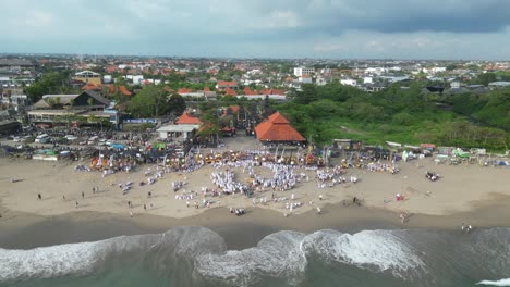 A-busy-beach-full-of-Balinese-people-during-the-Melasti-ceremony,-aerial