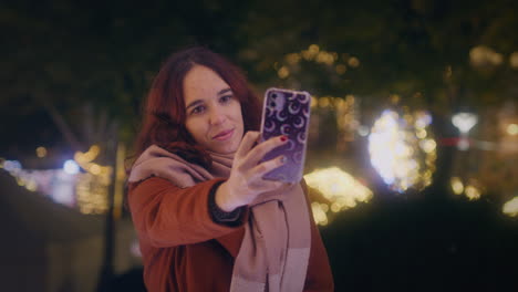 Mädchen-Macht-Ein-Selfie-Mit-Ihrem-Smartphone-Auf-Einem-Weihnachtsmarkt,-Nahaufnahme-In-Zeitlupe-Mit-Gimbal