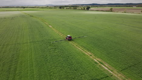 tractor-operating-a-continuous-spray-machine-containing-agrochemicals-on-a-farm-aerial-shot