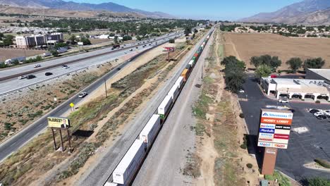 california-metro-link-train-carrying-cargo-through-a-mountain-city-in-the-desert-AERIAL-DOLLY-PAN
