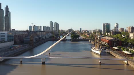 The-iconic-Woman's-Bridge,-Puente-de-la-Mujer,-in-Puerto-Madero,-Buenos-Aires,-framed-by-sleek-high-rises