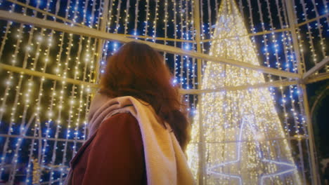 Mädchen-Blickt-Auf-Die-Lichter-Eines-Weihnachtsbaums-In-Zeitlupe-Mit-Rotierendem-Gimbal