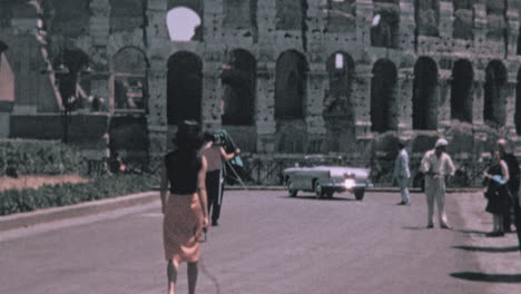 Turistas-Caminando-Por-La-Calle-Con-El-Coliseo-Al-Fondo-En-Roma-En-Los-Años-1960