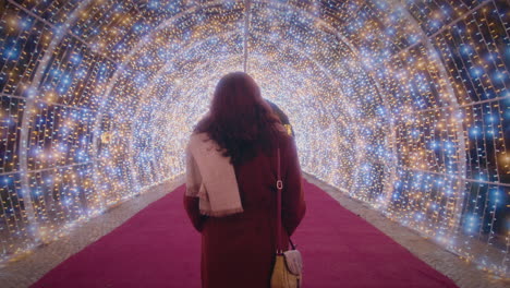 girl-walks-through-a-beautiful-tunnel-of-Christmas-lights-back-view-slow-motion