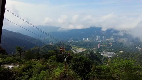 High-vantage-view-of-cable-car-system-above-a-township-on-the-route-to-the-mountaintop-luxury-complex-of-Resorts-World-Genting,-Malaysia