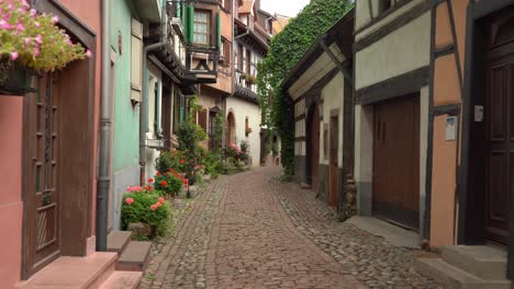 En-Eguisheim-Es-Agradable-Pasear-Por-Las-Estrechas-Calles-Adoquinadas-Llenas-De-Hermosas-Casas-Antiguas-Con-Entramado-De-Madera,-Ventanas-Y-Balcones-De-Madera-Adornados-Con-Geranios.