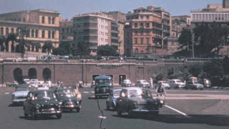 Avenida-Principal-De-La-Ciudad-Llena-De-Tráfico-De-Coches-Clásicos-En-Roma-En-Los-Años-1960