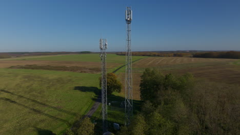 Two-cellular-towers-in-the-middle-of-the-french-fields,-aerial-circle-view
