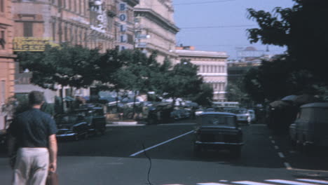 Ein-Mann-Wartet-In-Den-1960er-Jahren-Auf-Dem-Bürgersteig-Darauf,-Eine-Straße-Im-Rom-Zu-überqueren