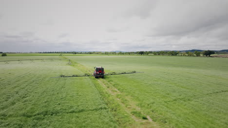 tractor-operating-a-continuous-spray-machine-on-a-farm-rotating-aerial-shot