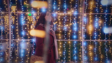 girl-walks-through-a-beautiful-tunnel-of-Christmas-lights-side-view-slow-motion-shot