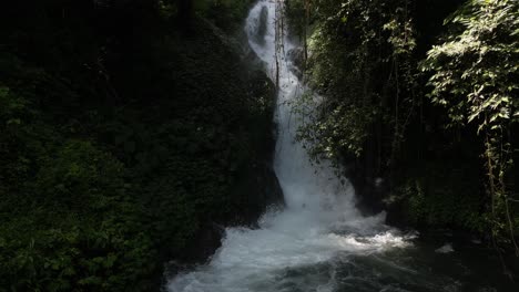 Hidden,-overgrown-waterfall-in-the-jungle-in-North-Bali-during-the-summer,-aerial