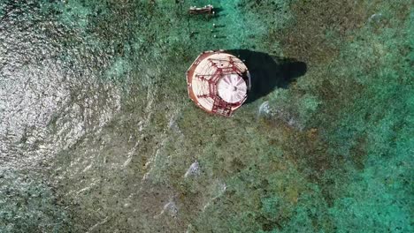 A-fly-over-drone-shot-of-an-abandoned-lighthouse,-in-a-remote-area-of-the-Caribbean-Sea,-near-Bimini,-Bahamas