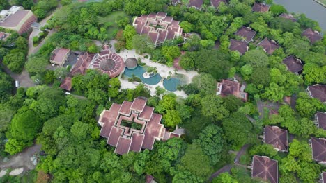 A-top-down-flyover-drone-shot-over-a-Resort-and-Golf-Course,-having-unique-Central-American-style-buildings-and-rooftops,-surrounded-by-dense-jungle,-in-Northern-Costa-Rica