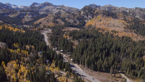 Sweeping-pan-of-a-road-that-goes-into-snowcapped-mountains-and-surrounded-by-yellow-aspens-with-other-autumn-colors