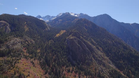 High-elevation-aerial-push-into-a-snowcapped-mountain-with-yellow-aspen-trees-and-fall-colors